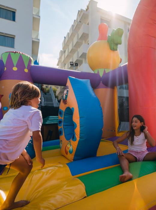 Bambini giocano su un castello gonfiabile colorato all'aperto.