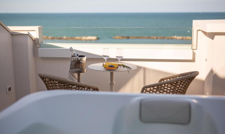 Vista mare con tavolino, due sedie e vasca idromassaggio.