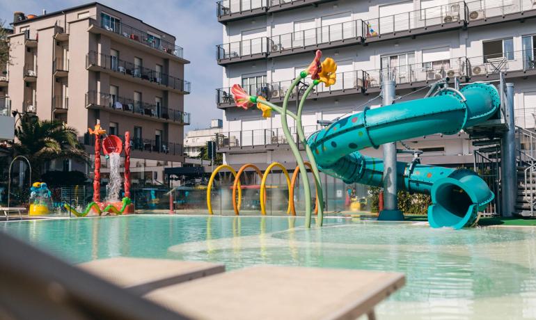 Piscina colorata con scivoli e giochi d'acqua, atmosfera vivace e divertente.