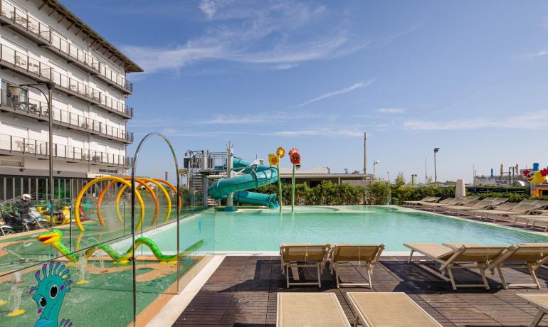 Piscina con scivoli colorati e sdraio, atmosfera estiva e divertente.