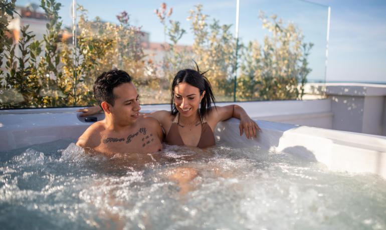 Happy couple relaxing in an outdoor hot tub, enjoying the sunshine.