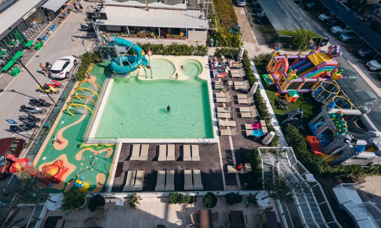 Piscine animée avec toboggans, jeux colorés et transats ensoleillés.