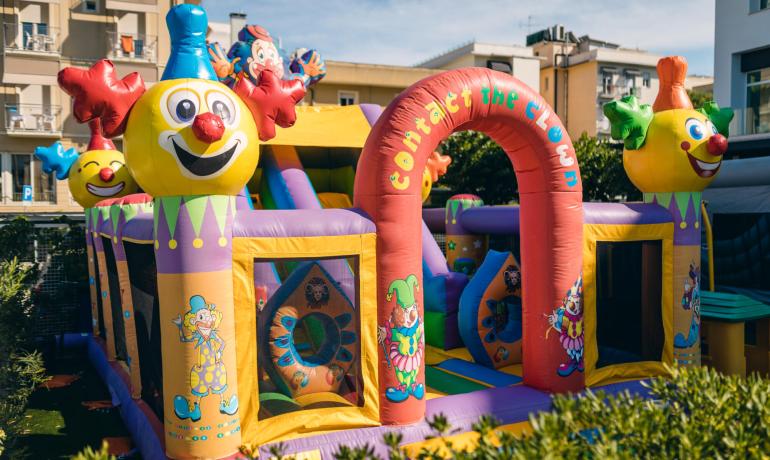 Castello gonfiabile colorato con clown allegri in un parco giochi.