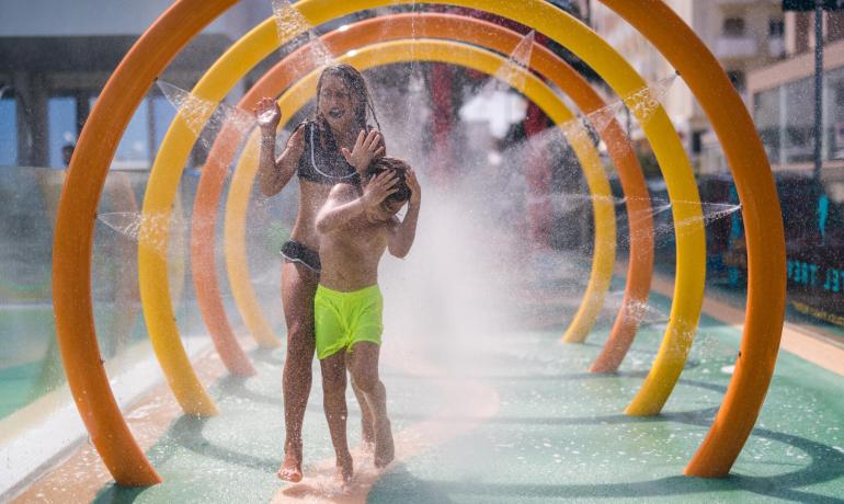 Kinder spielen unter bunten Wassersprühern im Wasserpark.