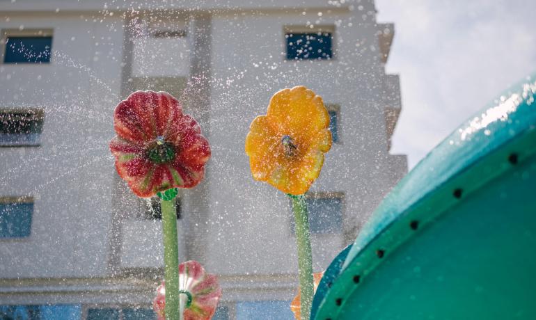 Fiori artificiali spruzzano acqua in una fontana davanti a un edificio.