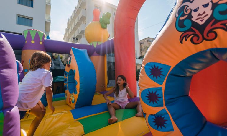 Bambini giocano su un castello gonfiabile colorato all'aperto.