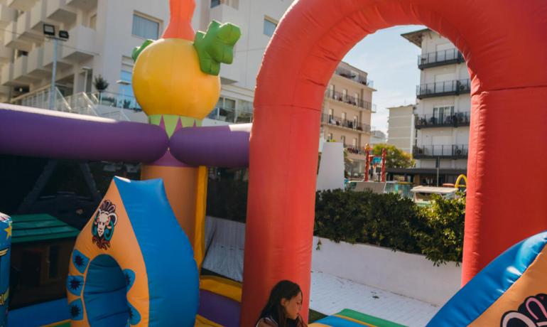 Bambini che giocano su un gonfiabile colorato in una giornata soleggiata.