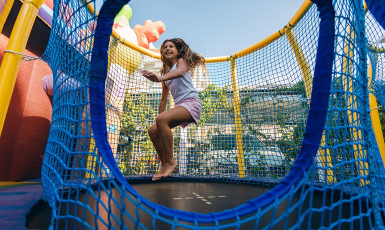 Fille s'amusant sur un trampoline entouré d'un filet de sécurité.