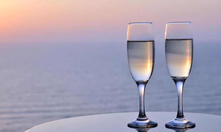 Due calici di champagne al tramonto sul mare, atmosfera romantica e serena.