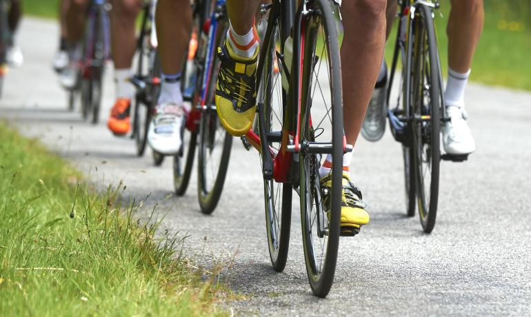 Ciclisti pedalano con energia su una strada, scarpe colorate illuminano il percorso.