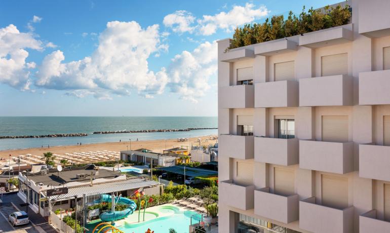 Hotel moderno con vista mare e piscina, vicino alla spiaggia.