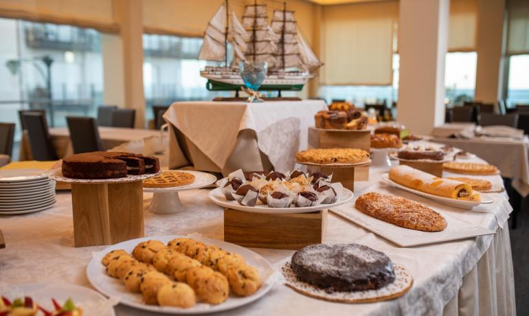 Varietà di dolci su un tavolo, con un modellino di nave sullo sfondo.