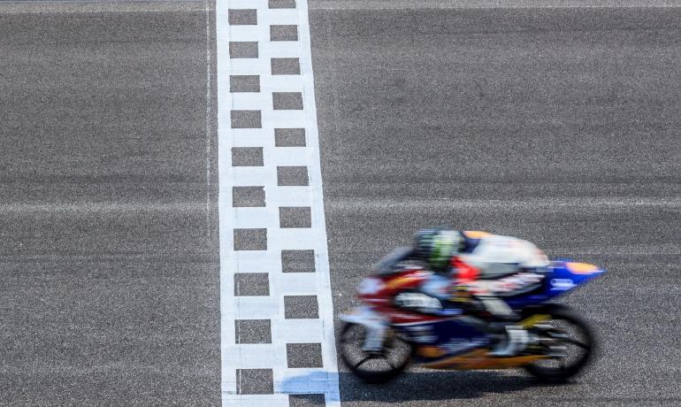 Moto attraversa il traguardo su pista asfaltata.
