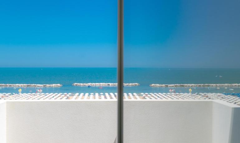 Vista mare serena con ombrelloni bianchi e cielo azzurro.