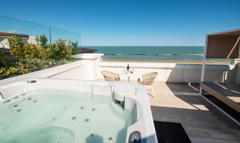 Terrazza con jacuzzi e vista mare, relax e lusso sotto il cielo azzurro.
