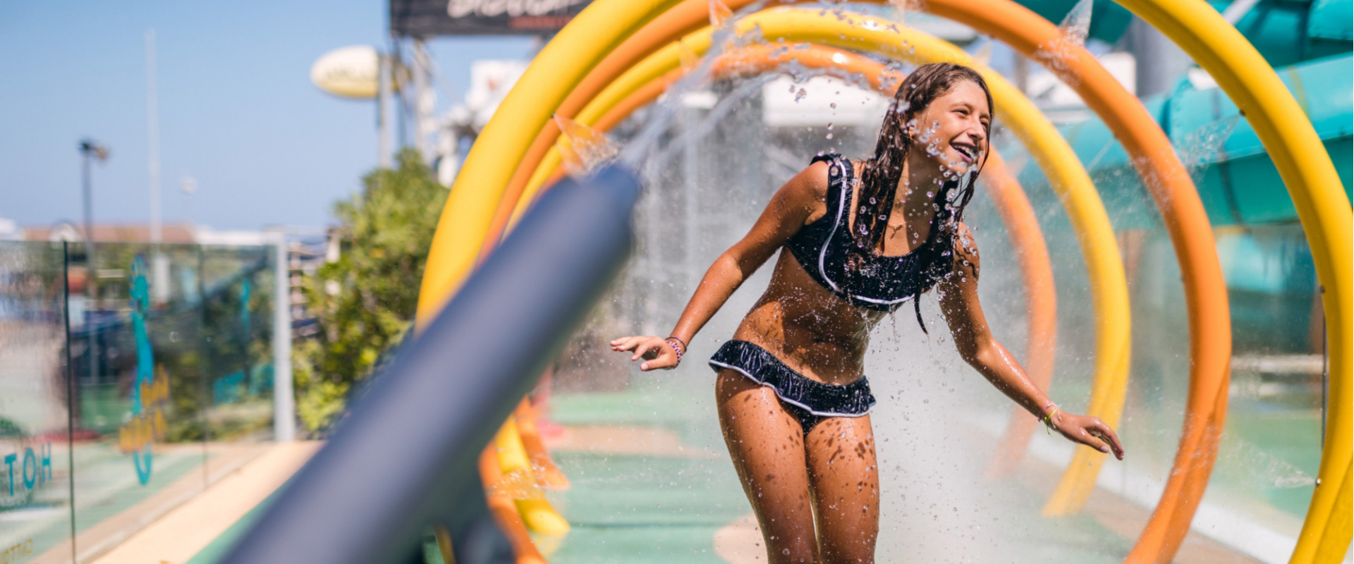 Ragazza si diverte sotto spruzzi d'acqua in un parco giochi acquatico.