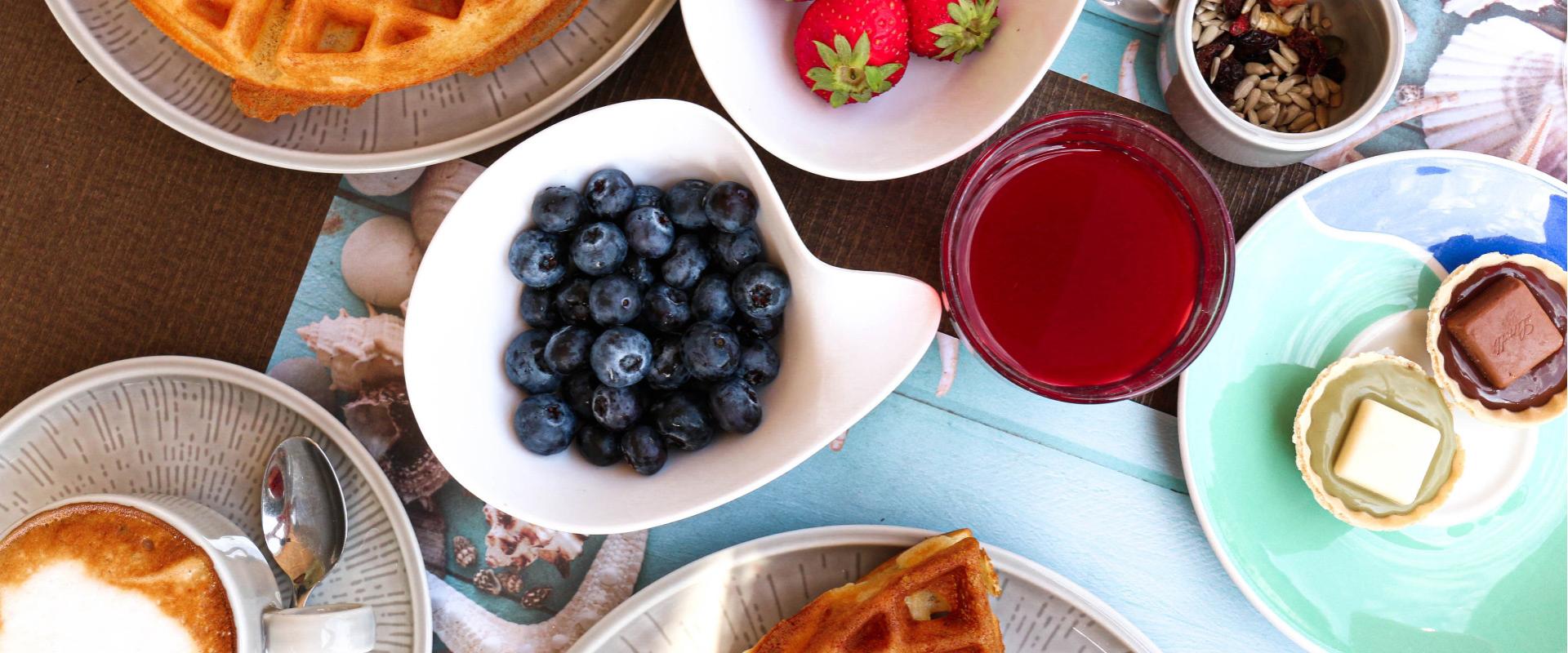 Petit déjeuner avec gaufres, baies, jus et café.