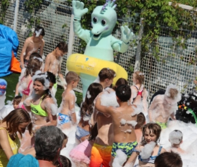 Festa in piscina con schiuma e un costume da alieno verde.