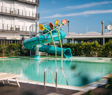 Piscina con scivolo acquatico e decorazioni floreali colorate.