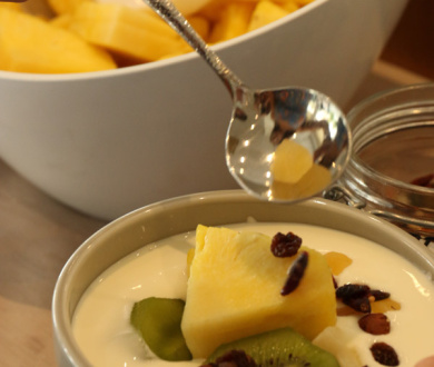 Yogurt con kiwi, ananas e frutta secca, servito in una ciotola.