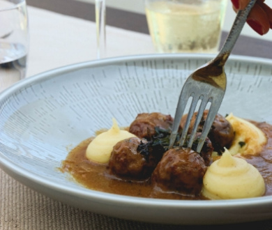 Polpette con purè di patate e salsa, servite in un piatto elegante.