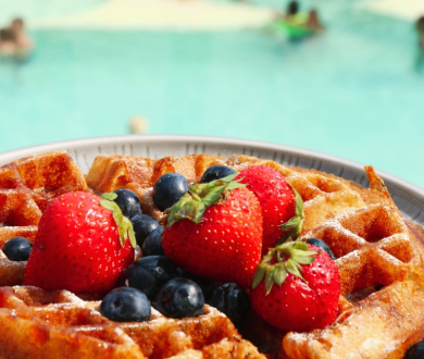 Waffle con fragole e mirtilli vicino a una piscina.
