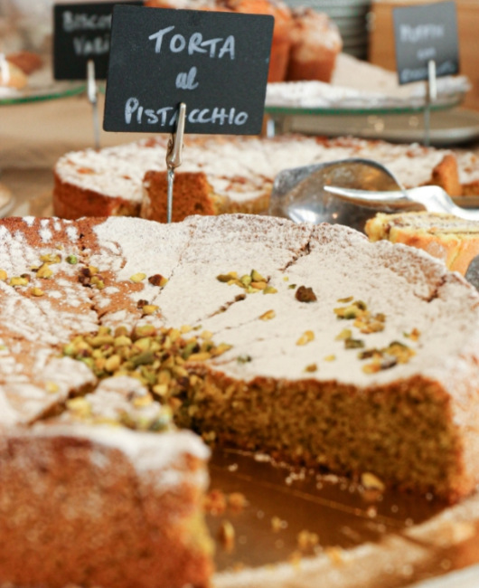 Torta al pistacchio con zucchero a velo e granella di pistacchi in esposizione.