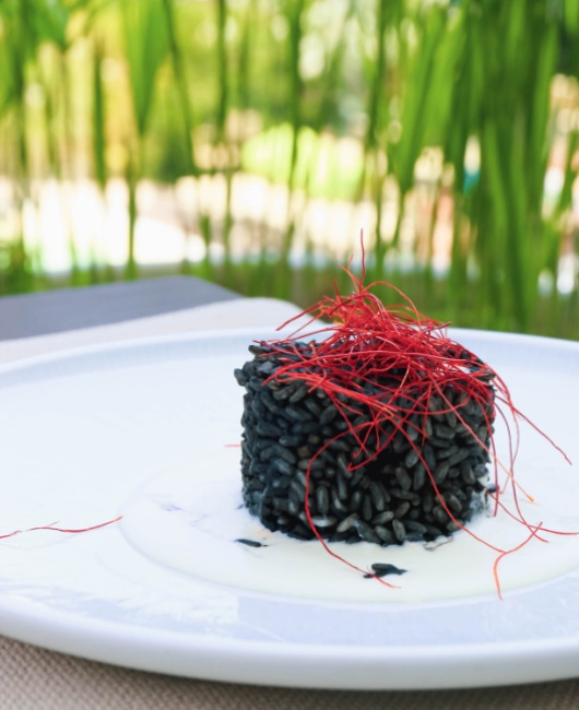 Risotto nero al nero di seppia con fili di peperoncino su piatto bianco.