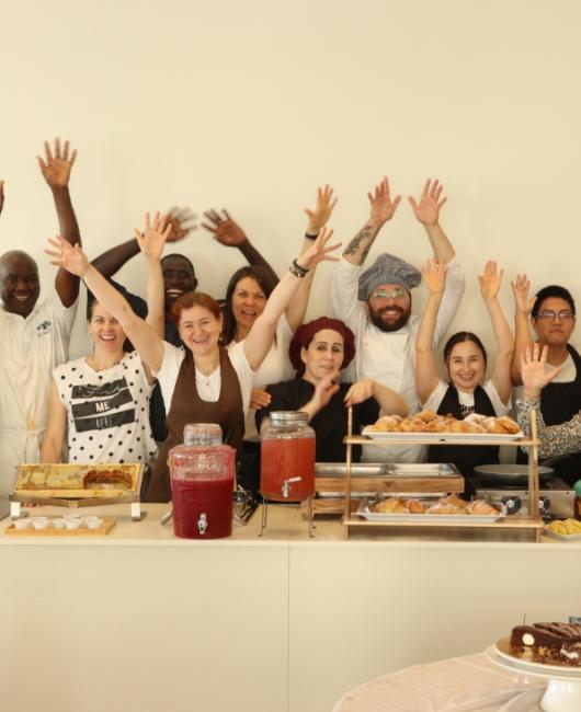 Gruppo di persone felici dietro un bancone con cibo e bevande.