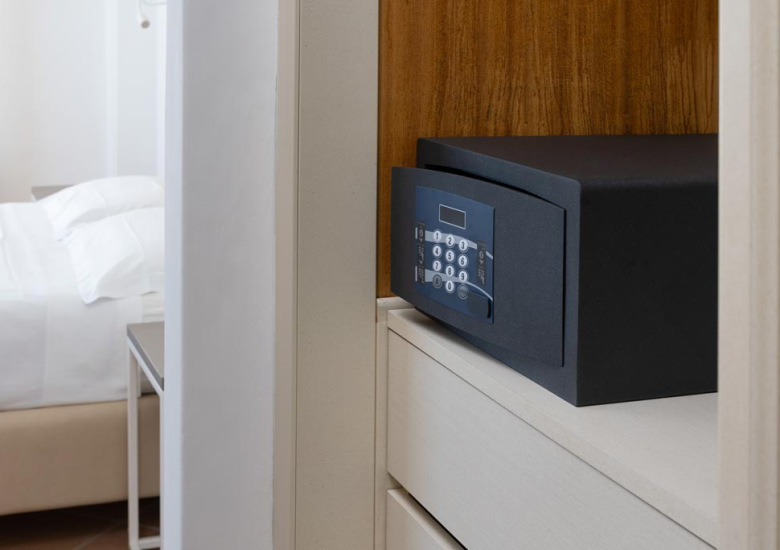 Cassaforte digitale in una stanza d'albergo con letto sullo sfondo.