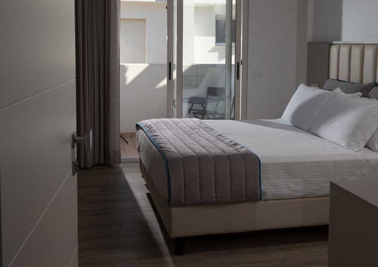 Camera da letto moderna con letto matrimoniale e accesso a un balcone.