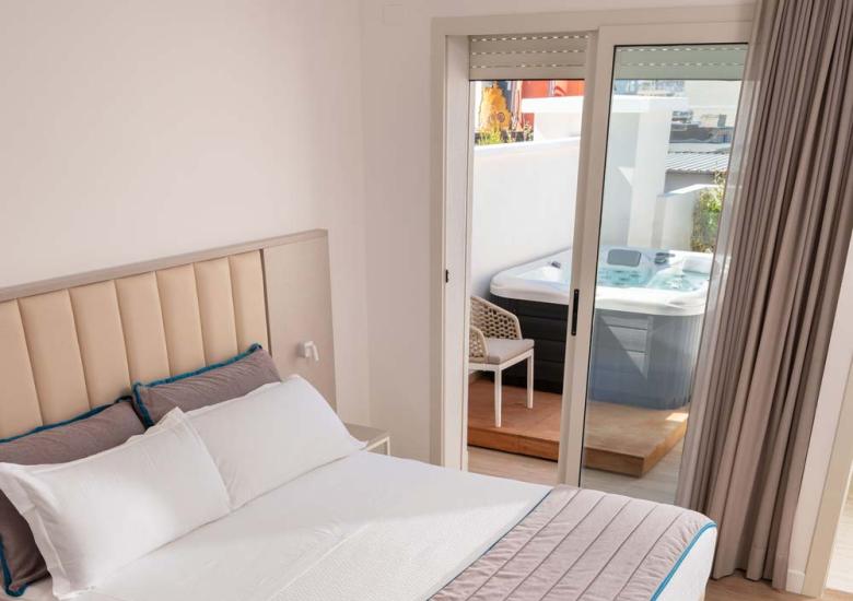 Camera moderna con letto matrimoniale e accesso a terrazza con vasca idromassaggio.